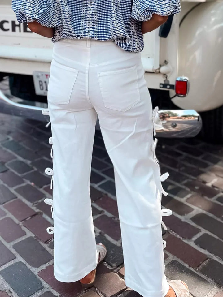 Person wearing white lace-up pants with a checkered top in an urban setting.