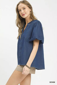 Woman wearing a blue denim shirt and beige shorts on a white background