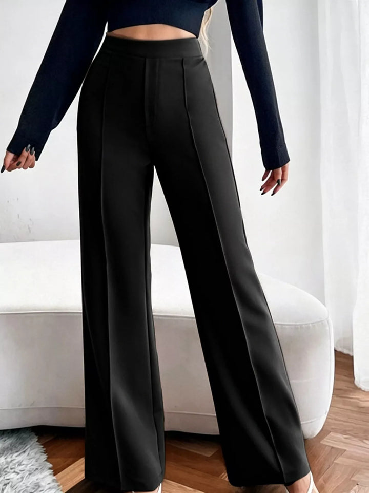 Person wearing black wide-leg pants with a blurred background