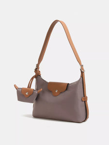 Gray crossbody bag with brown leather straps on a white background