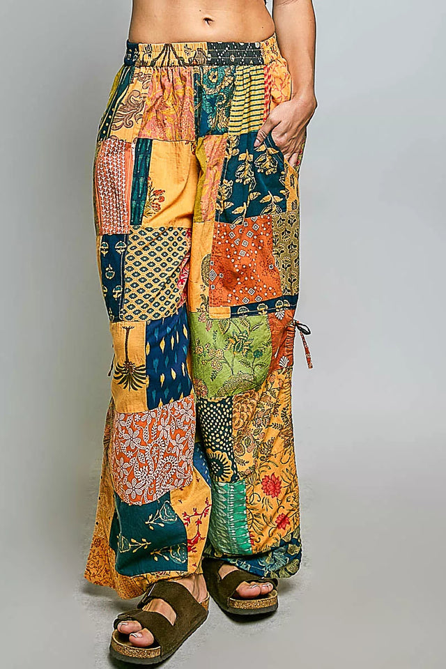 Colorful patchwork pants worn by a person on a gray background